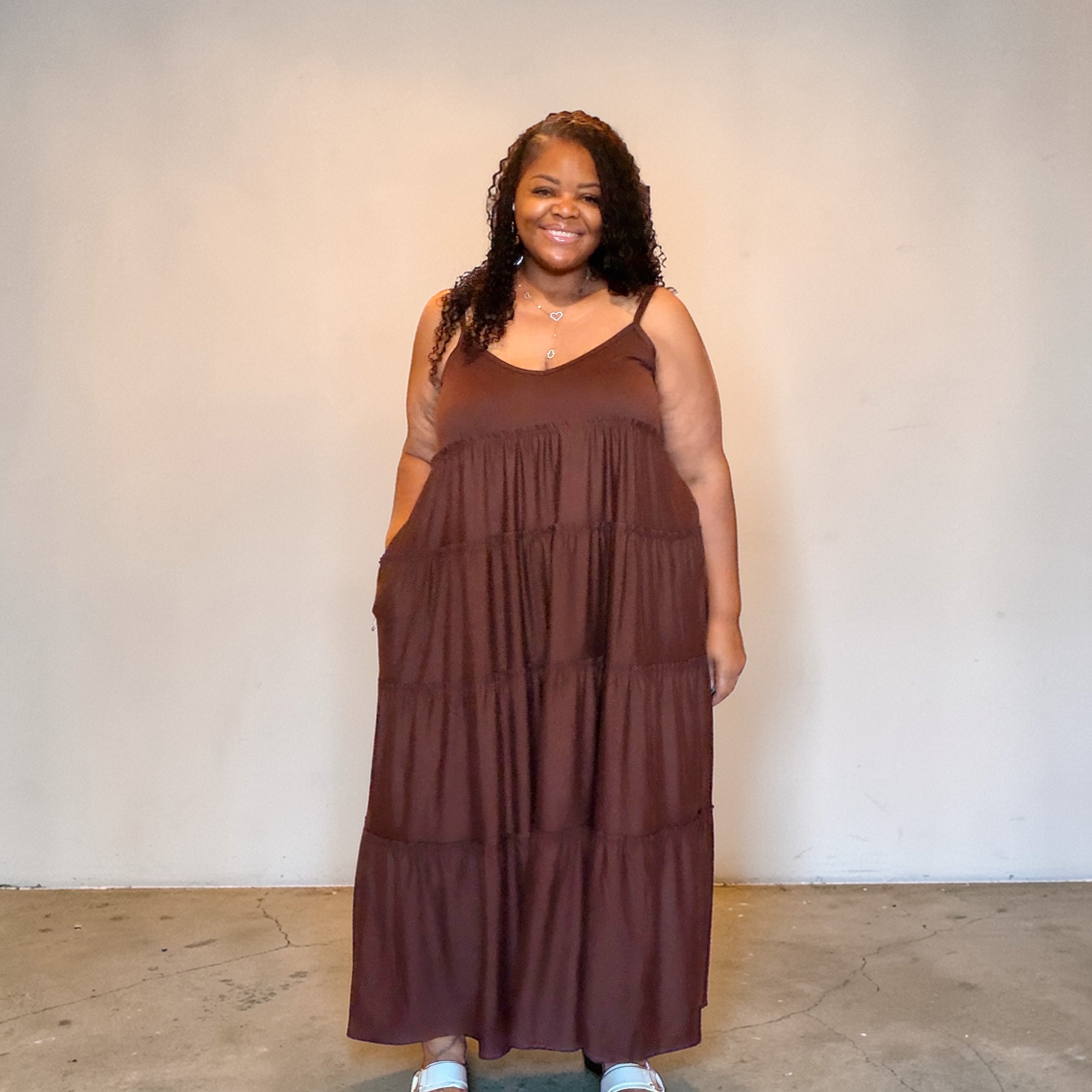 Woman wearing a brown tiered dress against a plain background